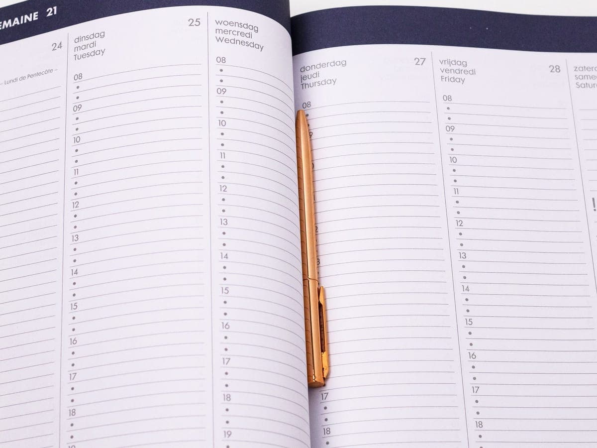 Ein aufgeschlagener Wochenkalender mit einem Stift in der Mittelfalz.